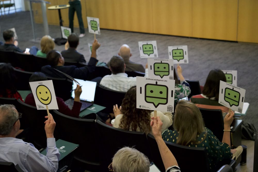 Audience holding up sign with a chatbot on one side an a smiley face on the other
